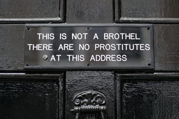 Sign on door, which reads: this is not a brothel. There are no prostitutes at this address.