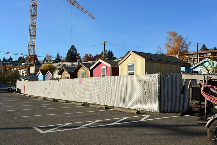 tiny homes screened from parking lot by a temporary fence